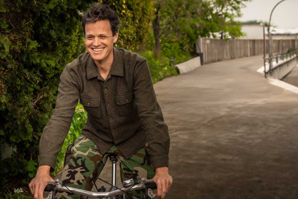 A smiling man riding a bicycle